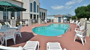 A rooftop pool area with lounge chairs and umbrellas, surrounded by a building with arched windows and a clock tower. - Quality Inn Bennettsville (Bennettsville)