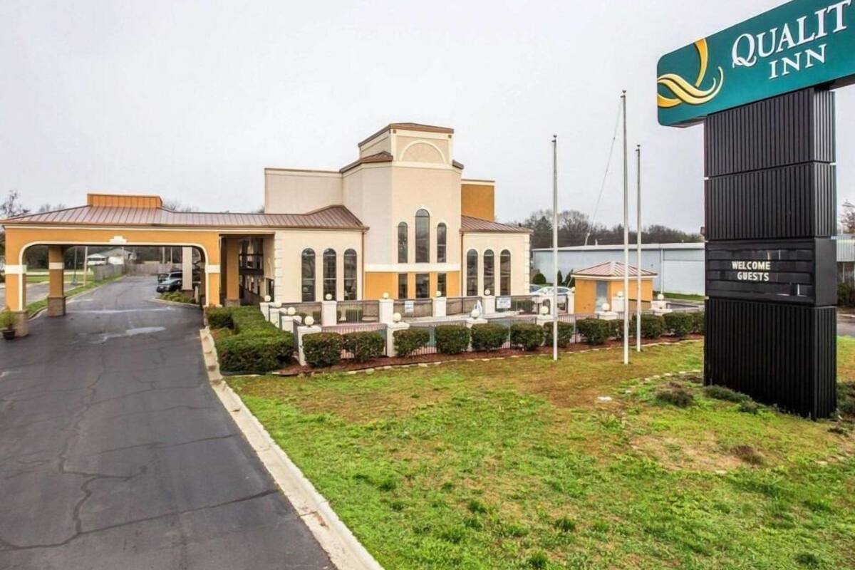 A hotel entrance with a sign reading 'Quality Inn,' a paved driveway, and a well-maintained lawn.
