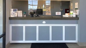 A hotel reception desk with a digital kiosk, informational brochures, and a sign welcoming visitors.