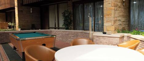 An indoor pool area with a pool table, chairs, and a table.