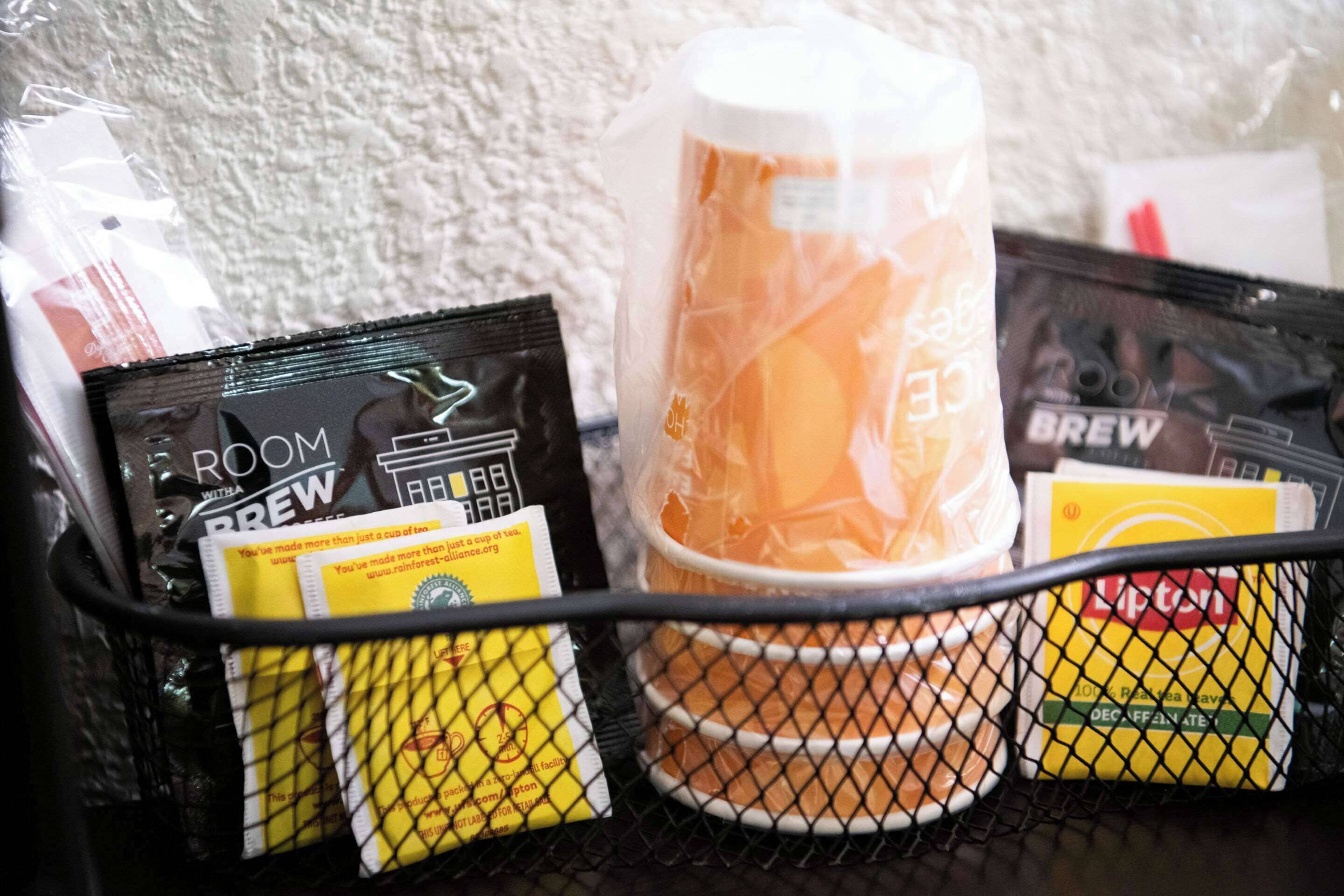 A coffee machine with a cup of coffee, a coffee pod, and a coffee bag on a table.