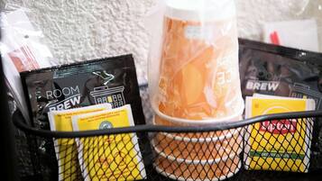 A coffee machine with a cup of coffee, a coffee pod, and a coffee bag on a table.