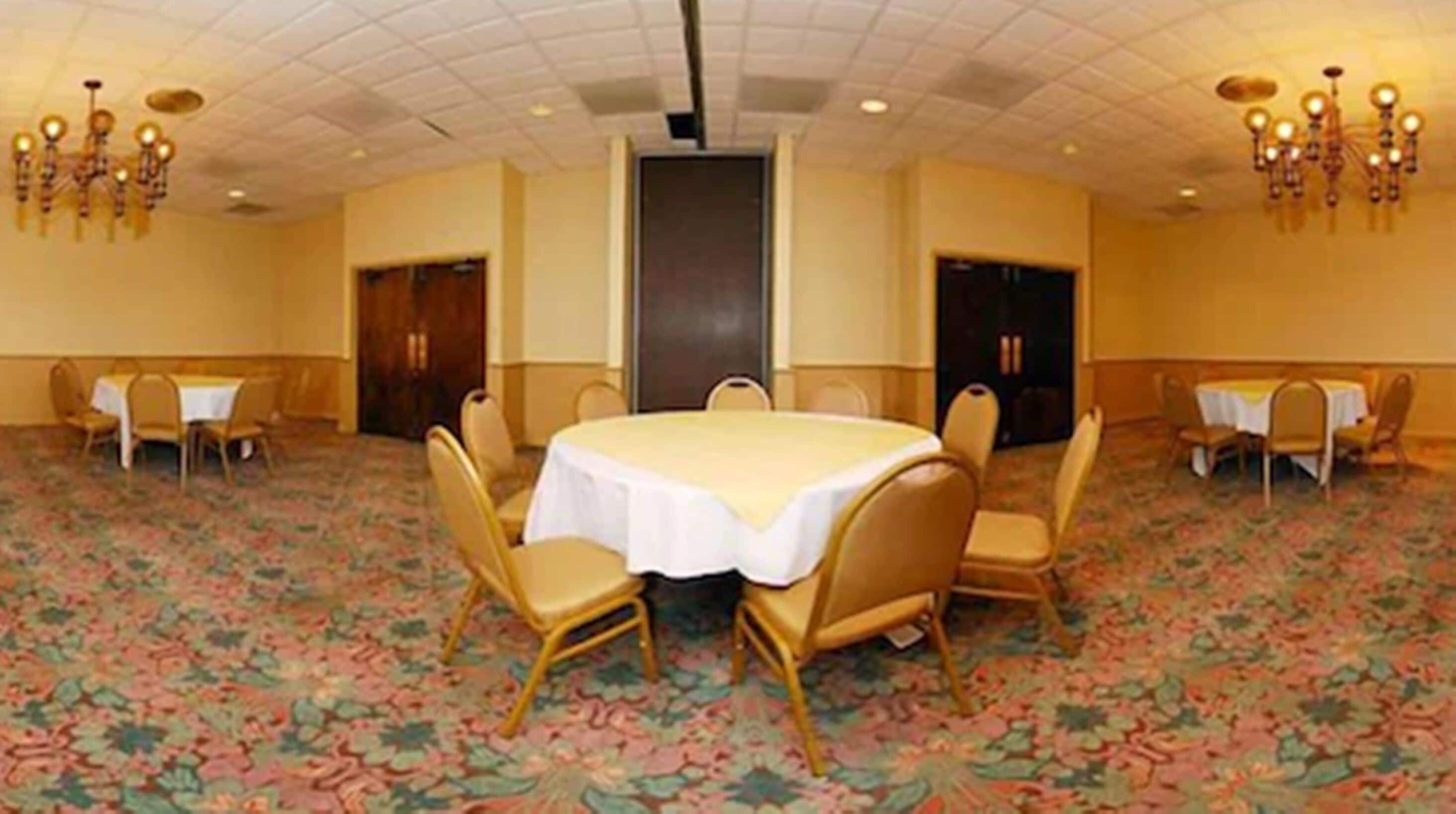 Una sala conferenze con un tavolo rotondo, quattro sedie e due lampadari.