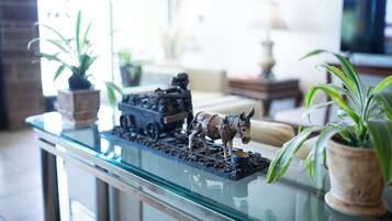 A model train set on a glass table with potted plants.