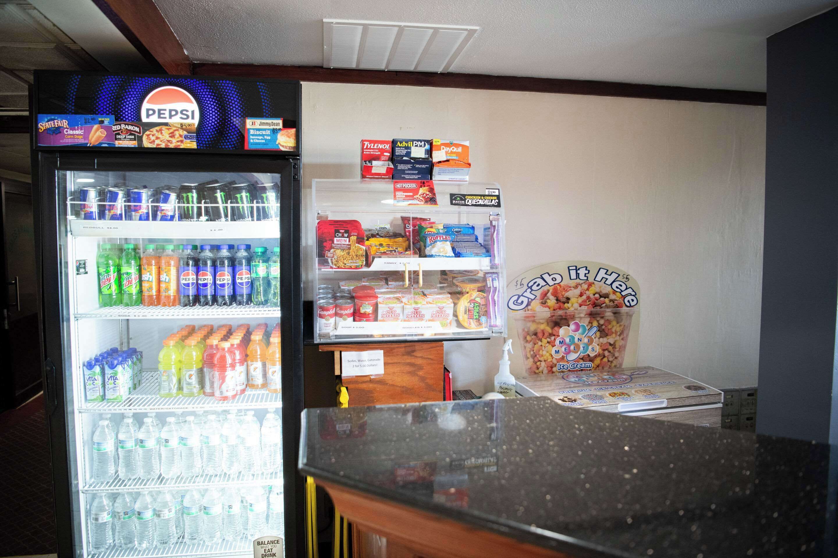 A vending machine with Pepsi and other drinks, a freezer with snacks, and a display of ice cream.