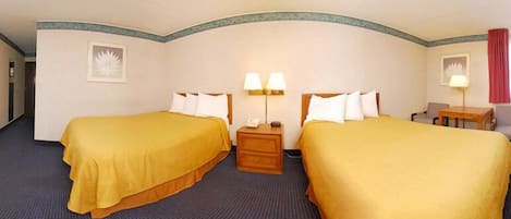 Habitación de hotel con dos camas, un escritorio y una silla.