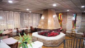 A restaurant with a stone fireplace, wooden tables, and chairs. - Quality Inn Somerset (Somerset)