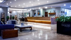 A hotel lobby with a reception desk, seating area, and a coffee table. - Oro Verde Cuenca (Cuenca)