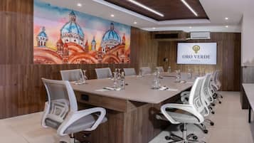 A conference room with a long table, white chairs, and a large screen displaying the logo "Oro Verde Cuenca".