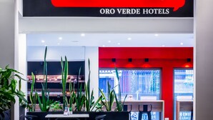 A Gourmet Deli in a hotel with a modern interior, including a seating area with chairs and a table, and a red accent wall. - Oro Verde Cuenca (Cuenca)
