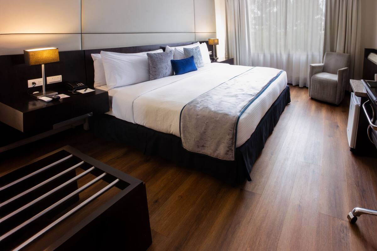A modern hotel room with a large bed, a desk, and a chair.