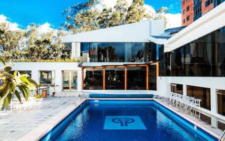 A modern pool area with a clear blue pool, a hot tub, and outdoor seating.