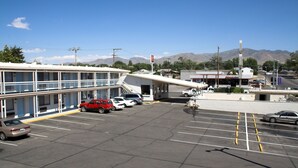 A motel with a two-story structure, a parking lot with several cars, and mountains in the background. - Holiday Motel (Winnemucca)