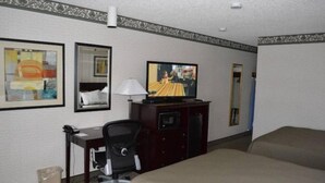 A hotel room with a bed, a desk with a chair, a television, and a trash bin. - Holiday Motel (Winnemucca)