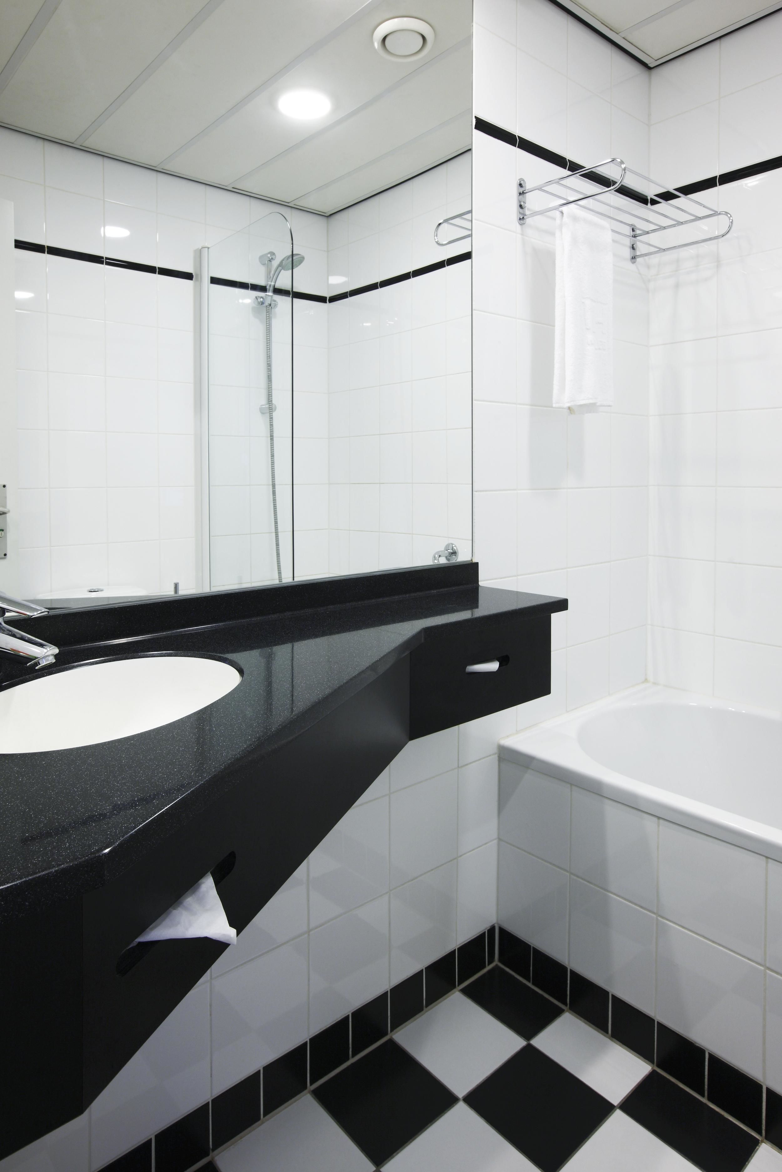 A modern bathroom with a black countertop, white sink, and a bathtub.