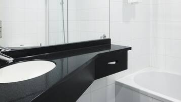 A modern bathroom with a black countertop, white sink, and a bathtub.