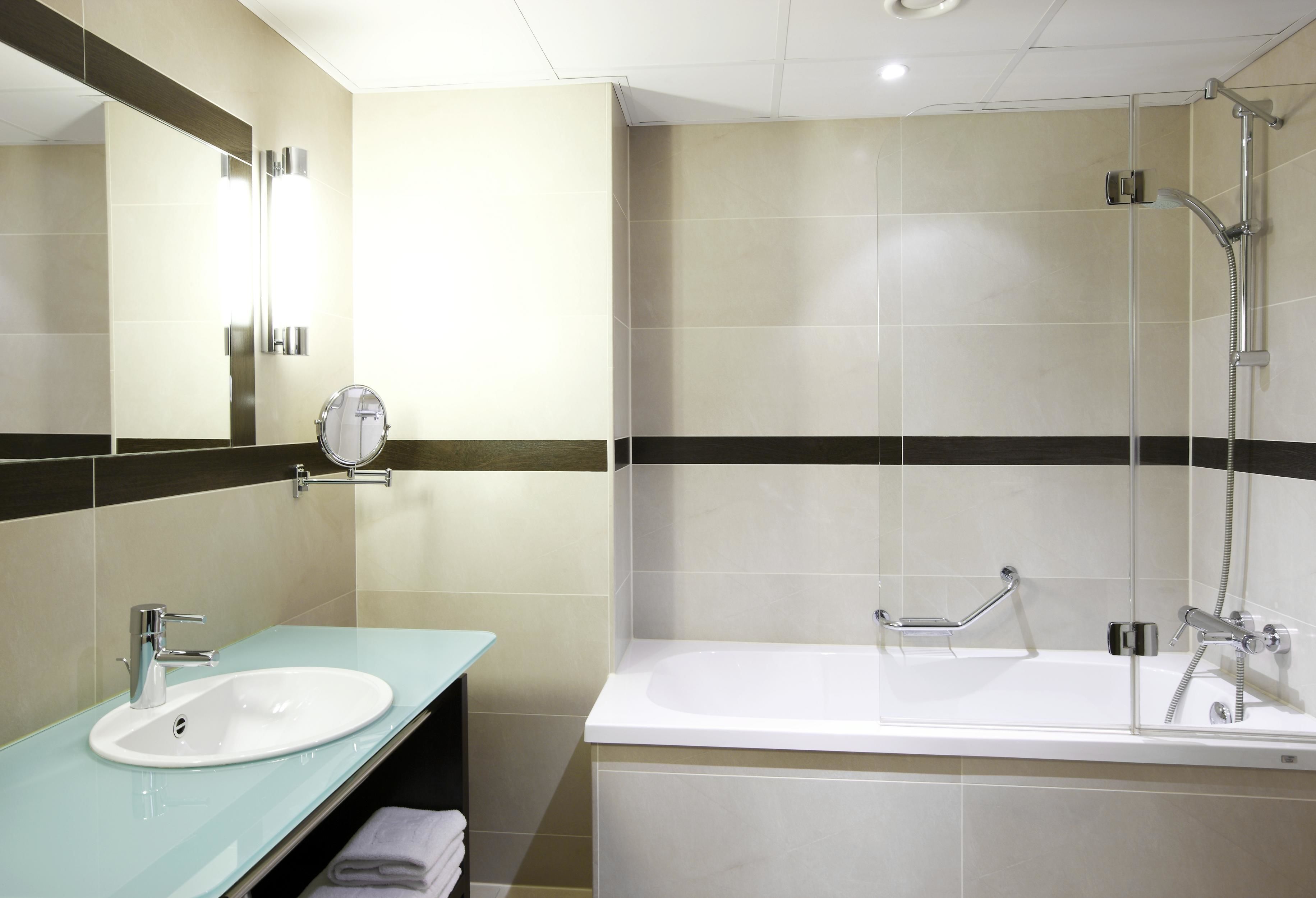 Een moderne badkamer met een douchecabine van glas, een wit wastafelmeubel en een grote spiegel.