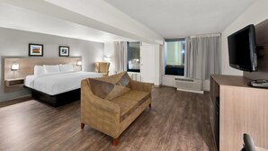 A hotel room with a bed, a sofa, a TV, and a desk. - Clarion Inn and Suites Convention Center Kearney (Kearney)