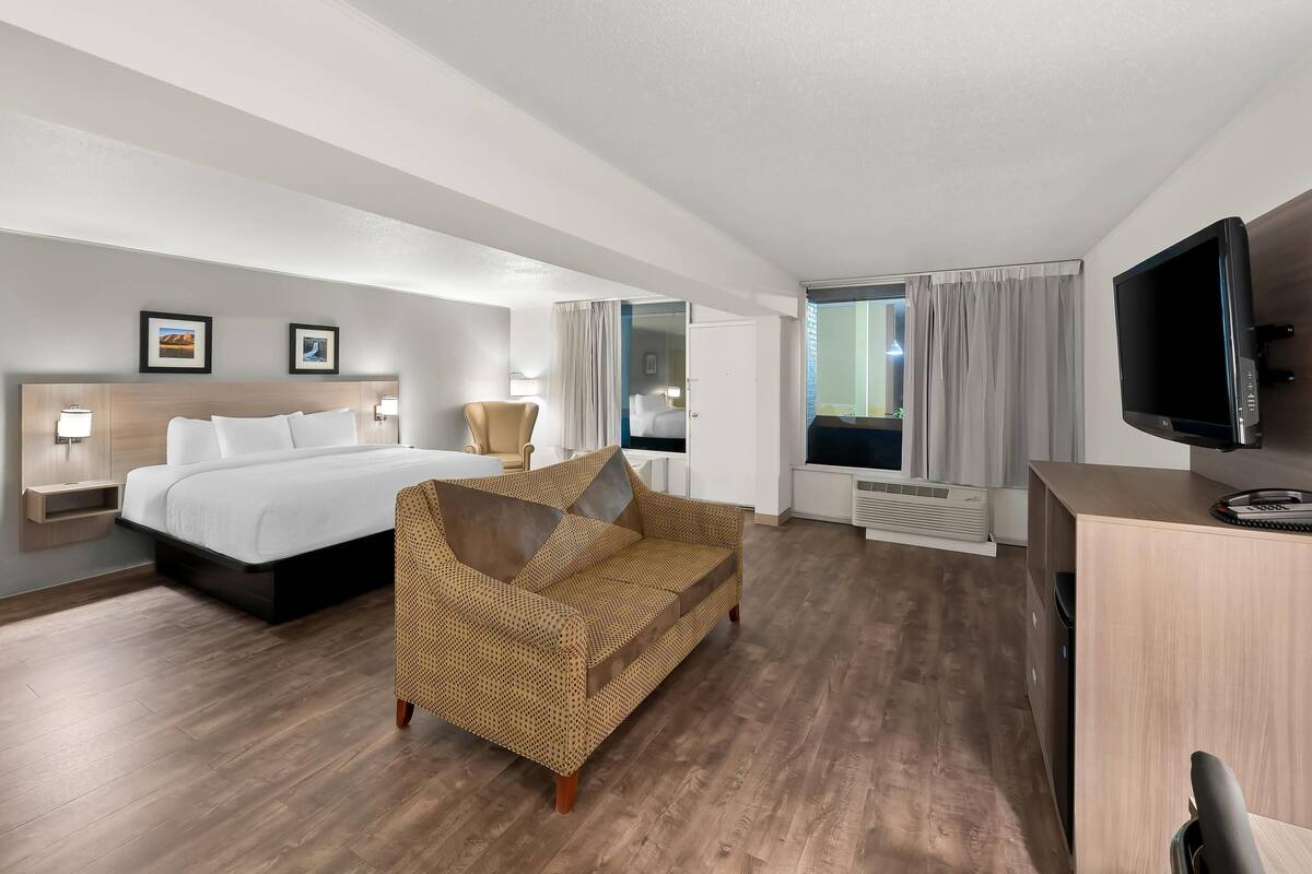A hotel room with a bed, a sofa, a TV, and a desk.