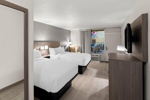 A hotel room with two beds, a TV, a desk, and a view of the outside. - Clarion Inn and Suites Convention Center Kearney (Kearney)