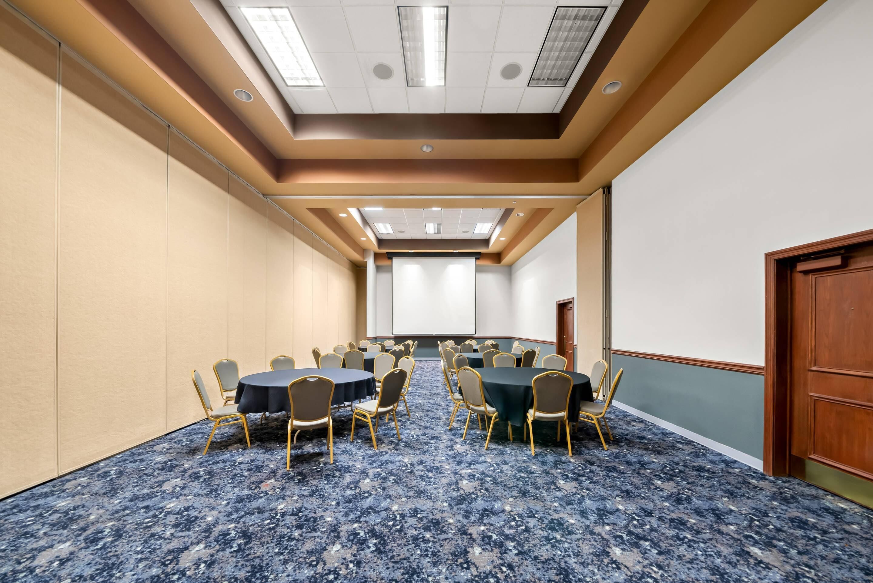 A conference room with a blue marble floor, beige walls, and a wooden door. Tables and chairs are arranged for meetings.
