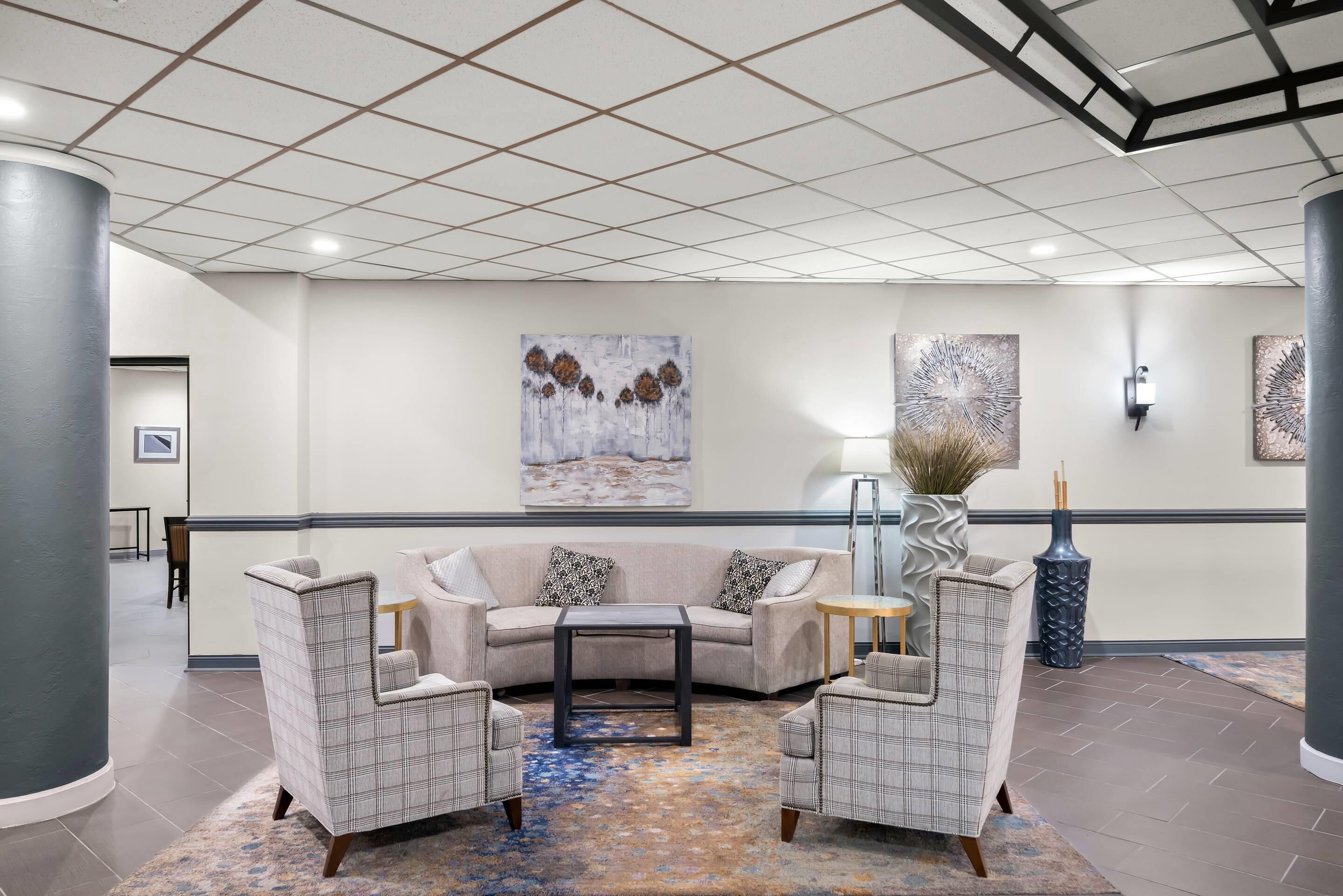 A lobby with a curved sofa, two armchairs, a coffee table, and abstract wall art.