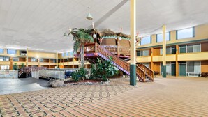 A spacious indoor area with a central staircase, multiple balconies, and a patterned carpet. - Clarion Inn and Suites Convention Center Kearney (Kearney)