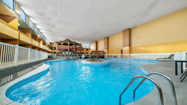 An indoor swimming pool with a central island, a wooden deck with a gazebo, and a balcony with railings. - Clarion Inn and Suites Convention Center Kearney (Kearney)