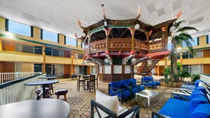A hotel lobby with a central wooden structure, seating areas, and a staircase. - Clarion Inn and Suites Convention Center Kearney (Kearney)