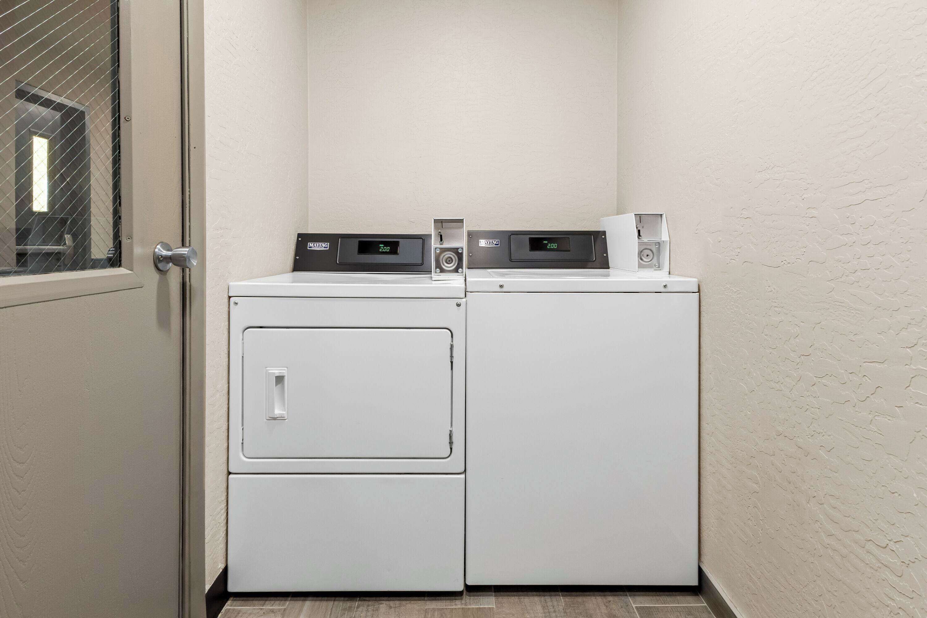 A laundry area with two stacked washers and dryers, a small window, and a door.