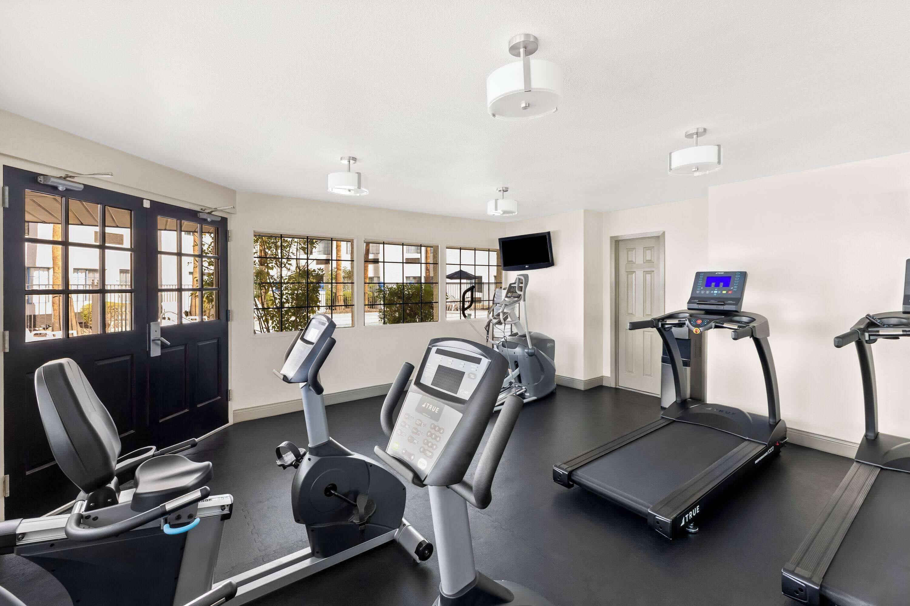 Een sportschool met loopbanden, een elliptische trainer en een hometrainer.