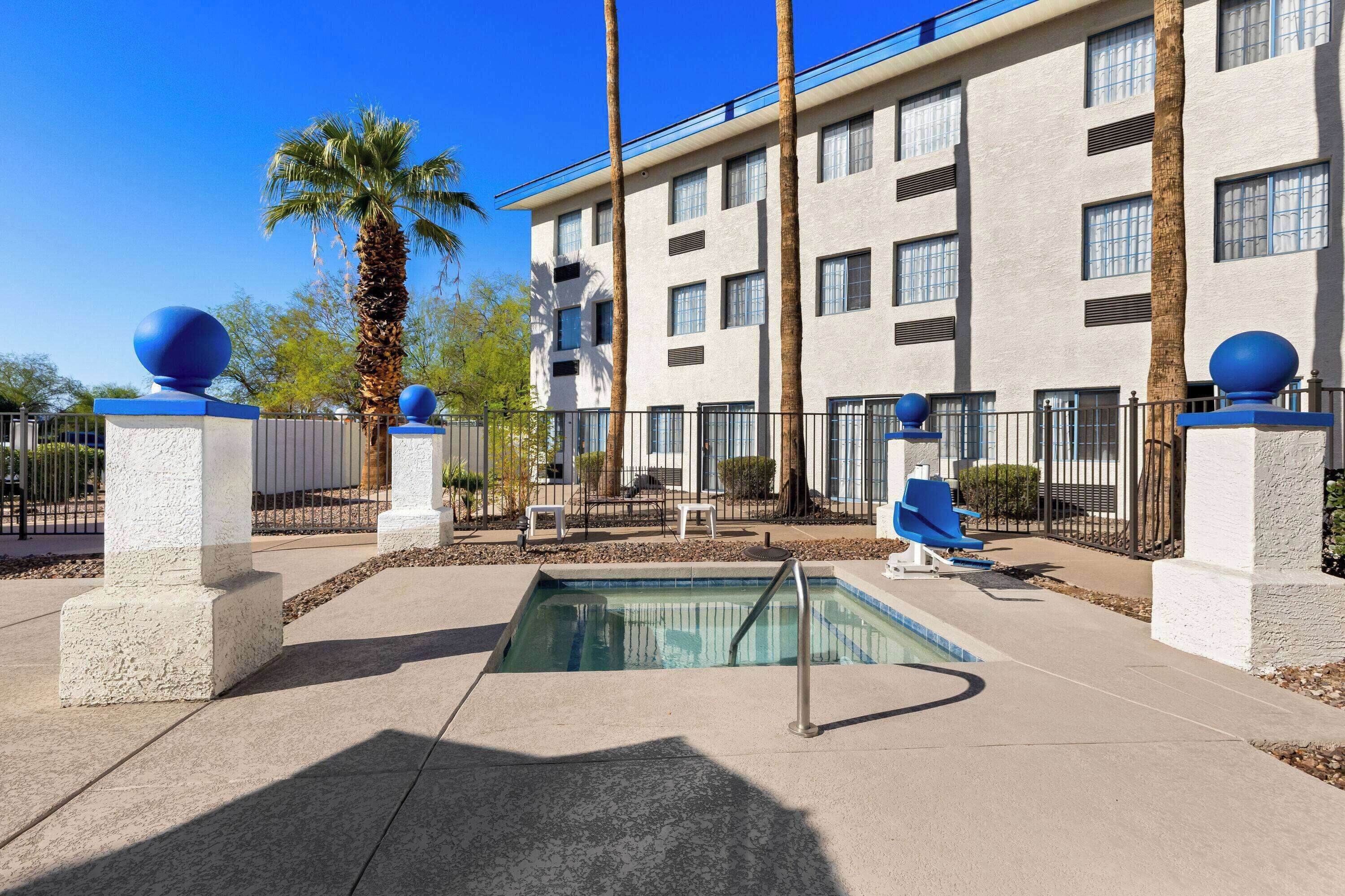 A hotel with a swimming pool, palm trees, and a modern building facade.
