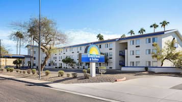 A Days Inn & Suites building with a clear sky, palm trees, and a parking lot.