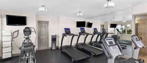 Une salle de sport équipée de tapis de course, d’un vélo elliptique et d’un vélo d’appartement.