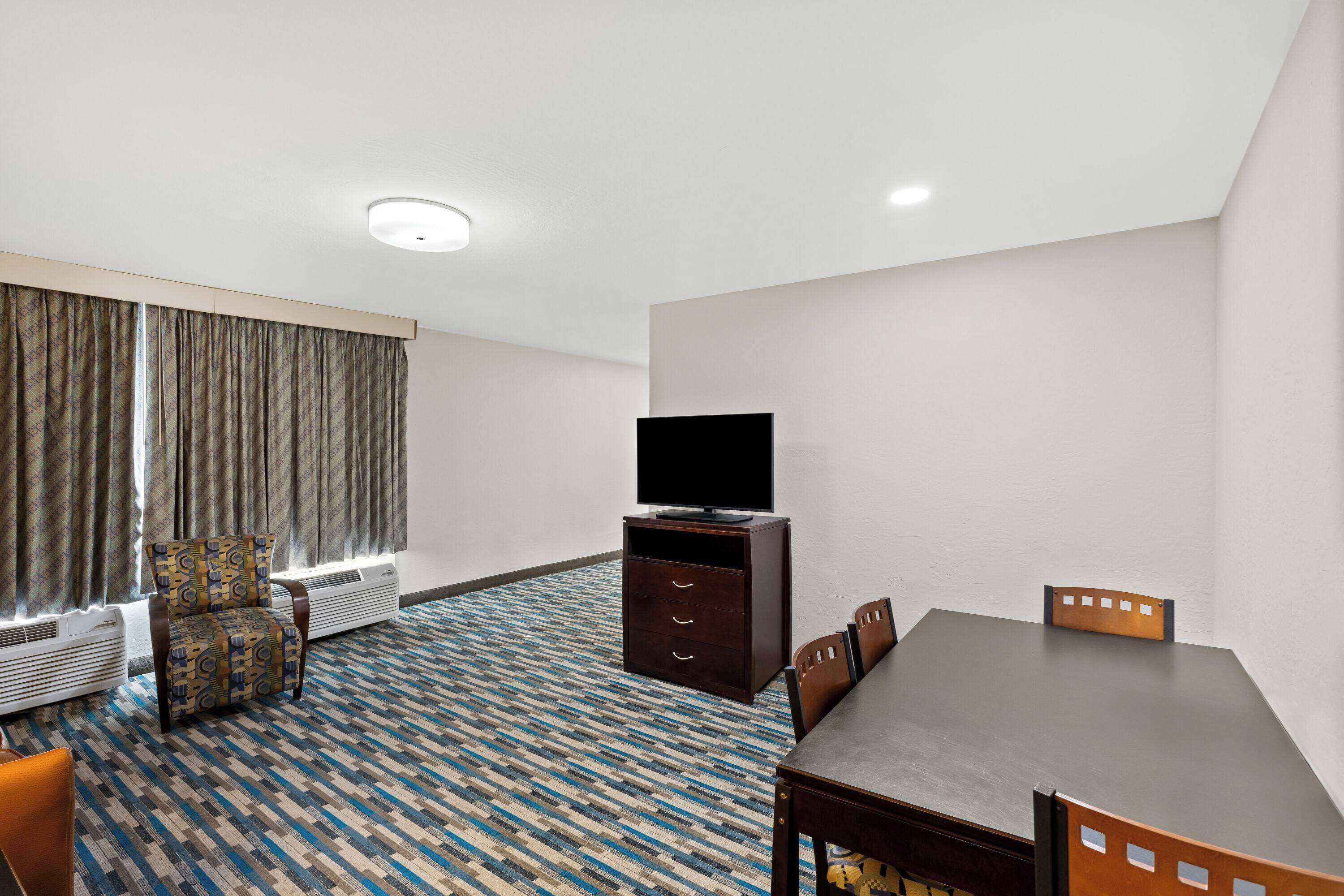 A hotel room with a large bed, a TV, a small table, and a chair.