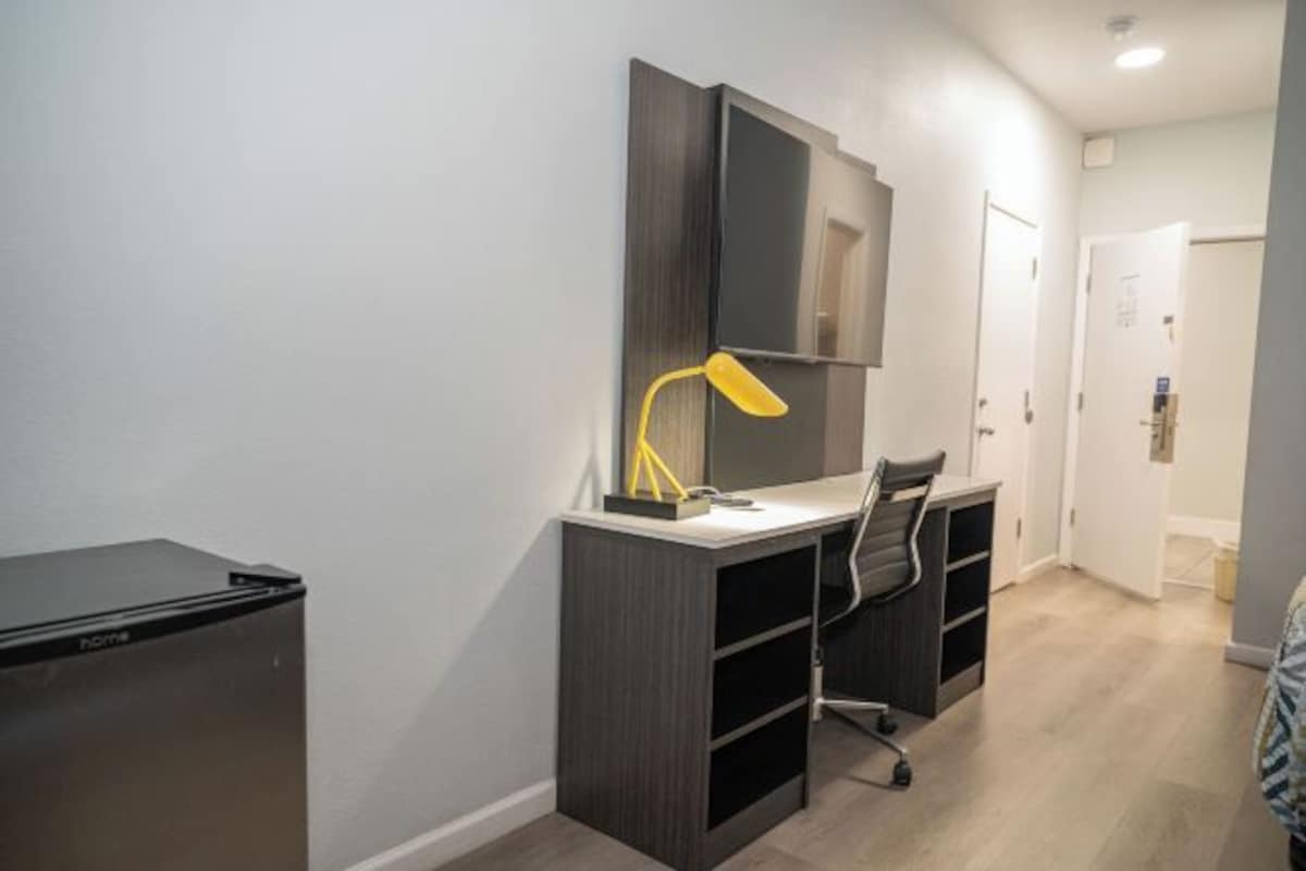 Espacio de oficina pequeño con escritorio, silla y televisor montado.