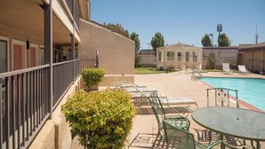 A hotel with a swimming pool, outdoor seating, and a small garden area.