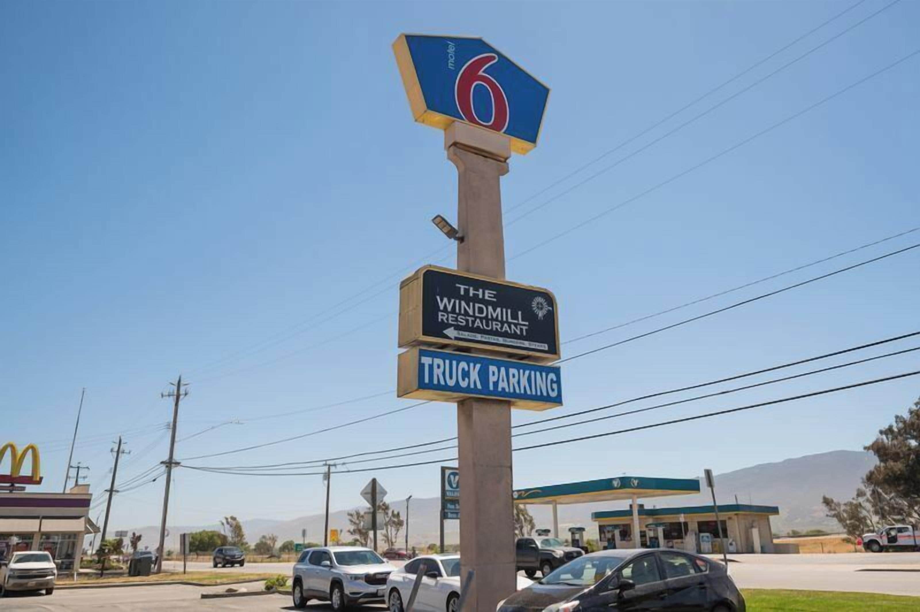 A motel sign with a windmill restaurant and a truck parking sign.