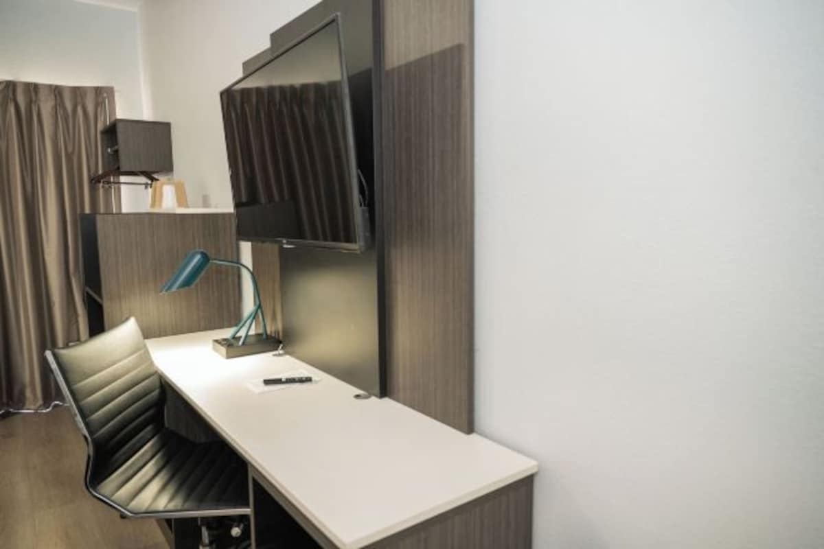 Habitación de hotel con escritorio, silla, televisor y lámpara.