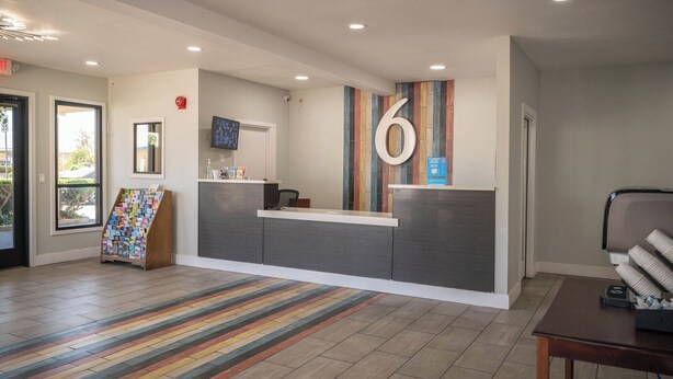 A reception area with a modern design, including a reception desk, a large number '6' sign, a flat-screen TV, and a colorful striped rug.