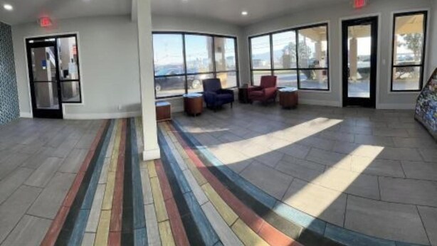 Un hall d’entrée spacieux, doté de grandes fenêtres, d’un sol rayé aux couleurs vives et d’un luminaire moderne au plafond.