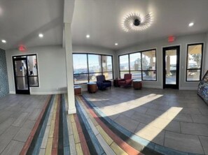 A spacious lobby with large windows, a colorful striped floor, and a modern ceiling light fixture.