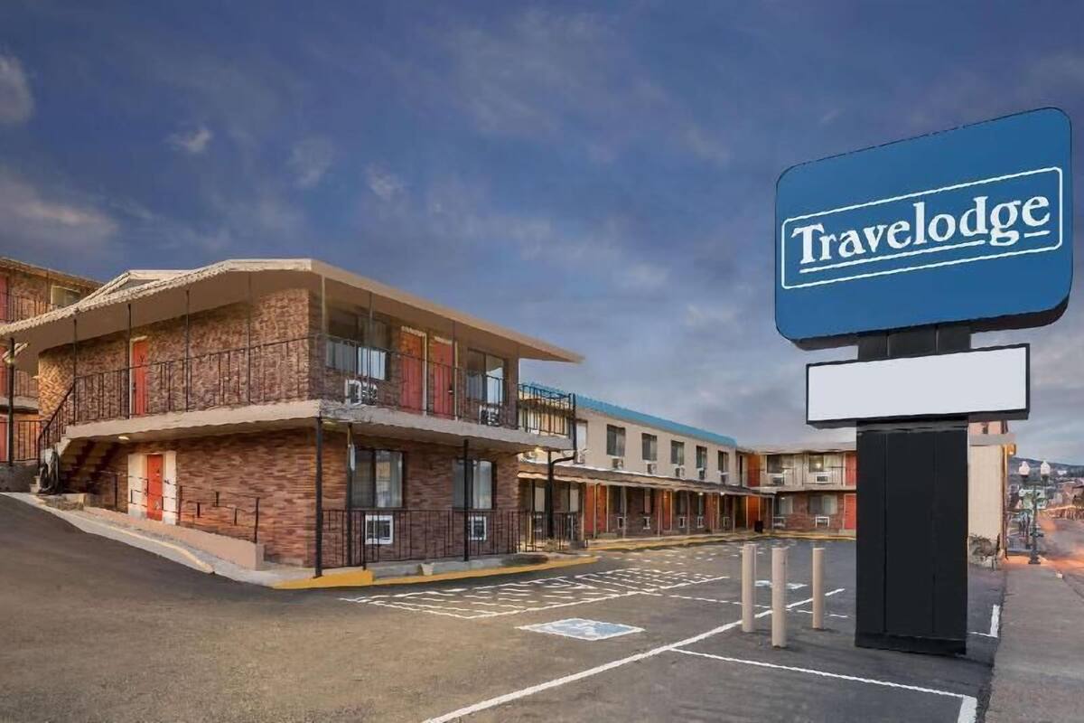 A Travelodge hotel with a brick facade, multiple balconies, and a parking lot.