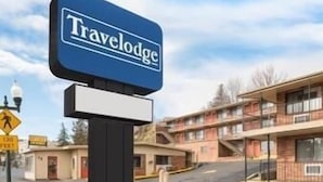 A Travelodge sign in front of a multi-story building with a parking lot.