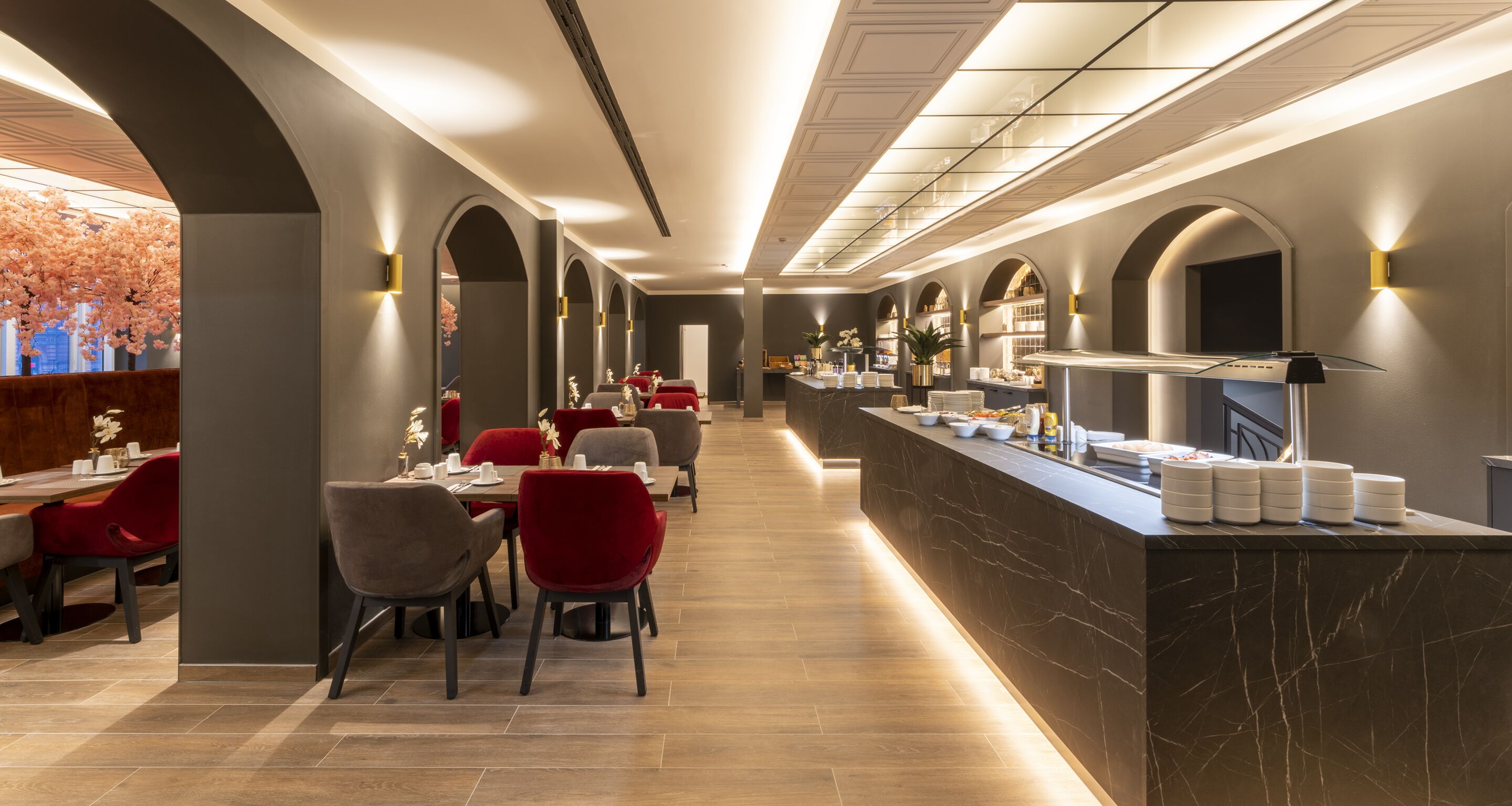 A modern restaurant with a long counter, red chairs, and a marble backsplash.