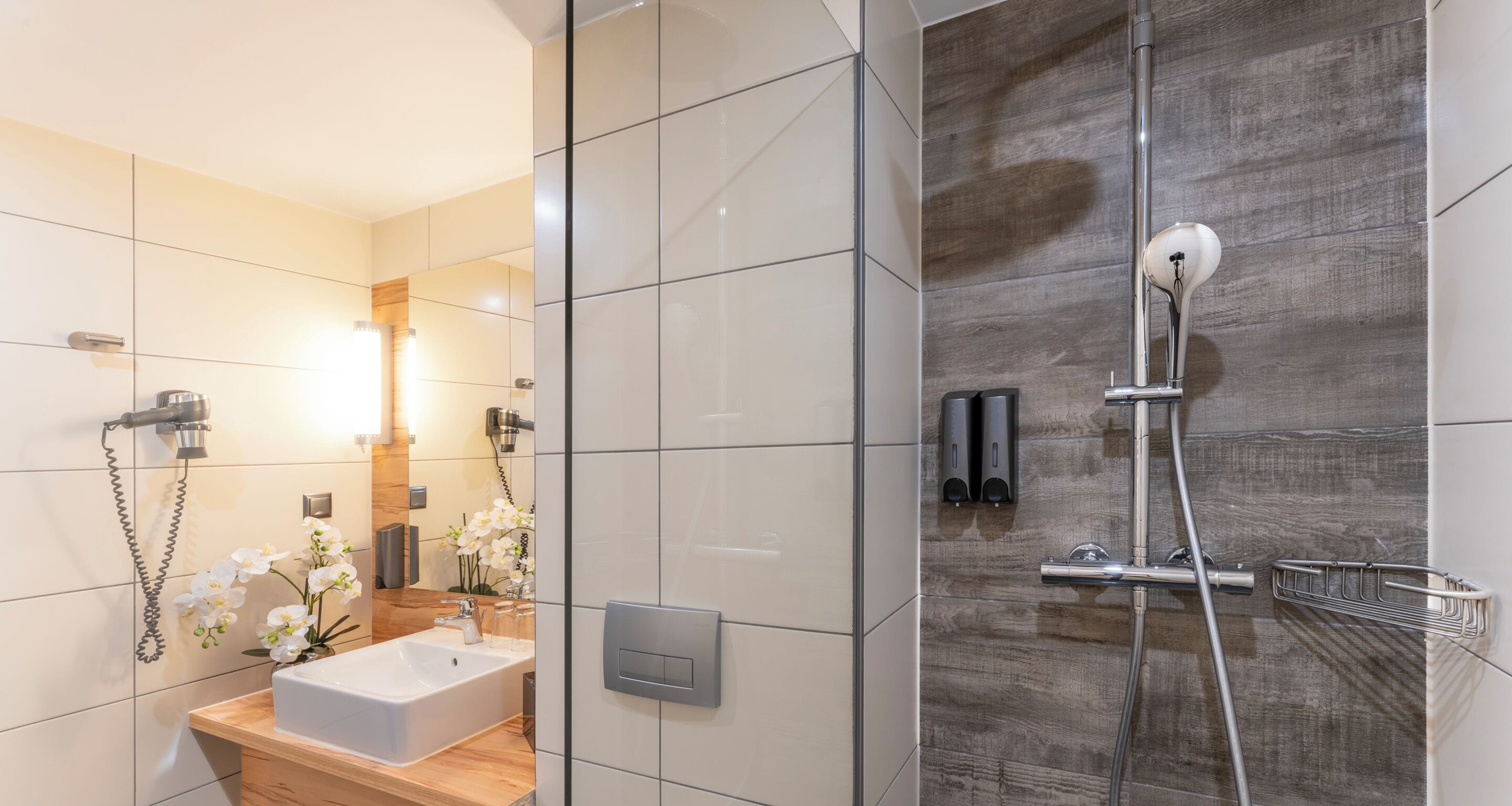 Un baño moderno con ducha, lavamanos y espejo.