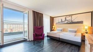 Una habitación de hotel con cama, una silla, un ventanal y vistas a la ciudad.