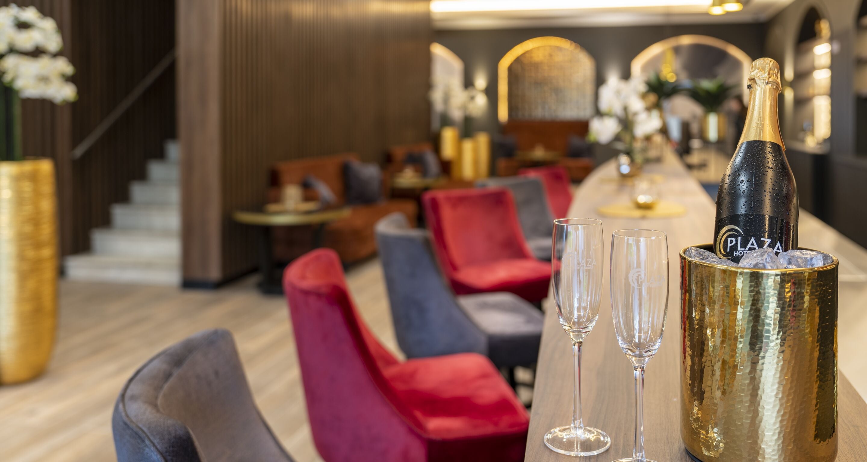 A bar area with a champagne bottle, glasses, and seating.