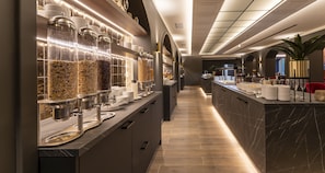 A modern hotel lobby with a marble reception desk, a food display with jars of snacks, and a plant in the corner. - PLAZA Premium Columbus Bremen (Bremen)