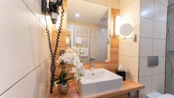 Un baño con lavamanos blanco, espejo y ducha.